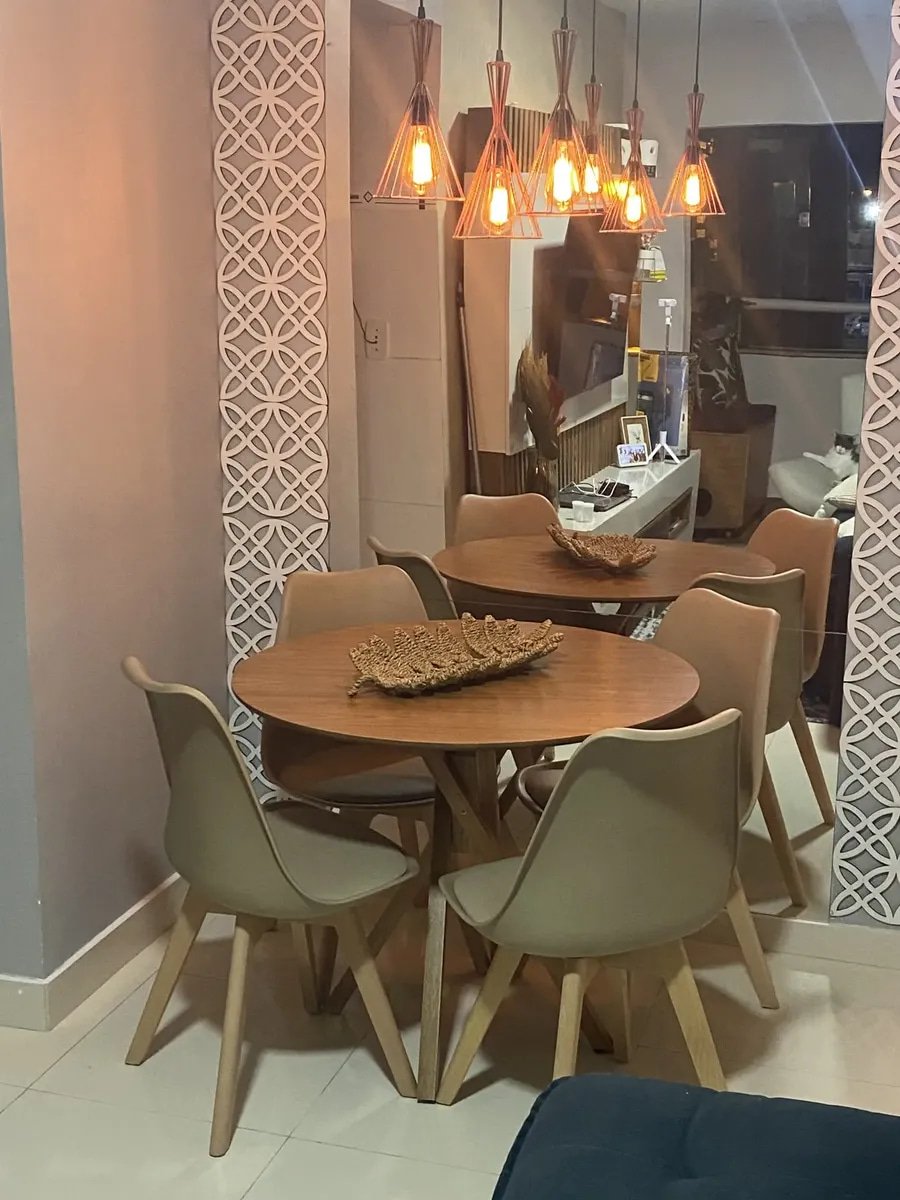 Sala de jantar com duas mesas redondas de madeira e cadeiras estofadas Leda nude com base de madeira e pendentes aramados